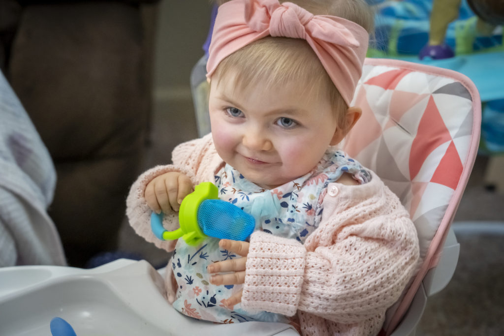 Real ZOLGENSMA patient Maisie holding a cup and sitting with support in a high
chair